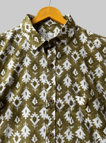 Load image into Gallery viewer, Green shirt with white pattern on a hanger against a wooden background