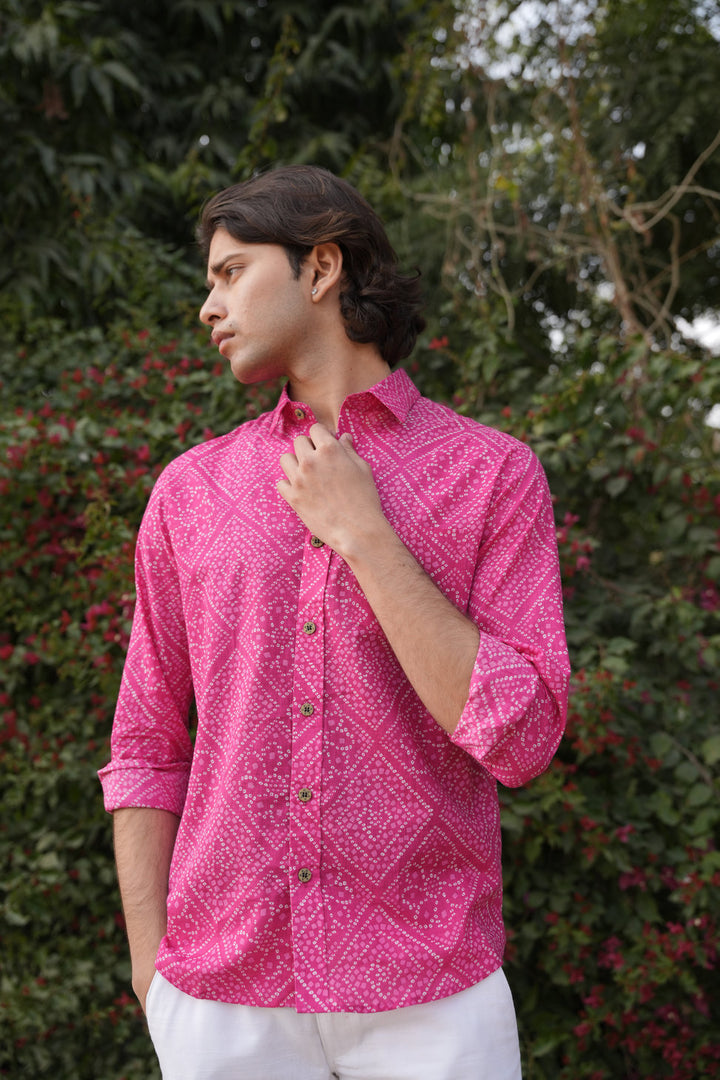 Person wearing a bright pink patterned shirt with a blurred green background