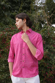 Person wearing a bright pink patterned shirt with a blurred green background