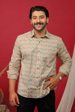Load image into Gallery viewer, Man wearing a beige floral printed full sleeve shirt with black jeans against a red background.
