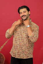Load image into Gallery viewer, Man wearing a brown paisley printed full sleeve shirt with black jeans against a red background.