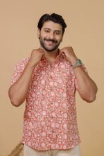 Load image into Gallery viewer, Man wearing a peach floral printed half sleeve shirt with beige trousers against a beige background.