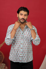 Load image into Gallery viewer, Man wearing a sky blue floral printed full sleeve shirt with black jeans against a red background.