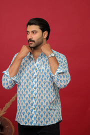 Man wearing a white and blue block printed full sleeve shirt with black jeans against a red background.