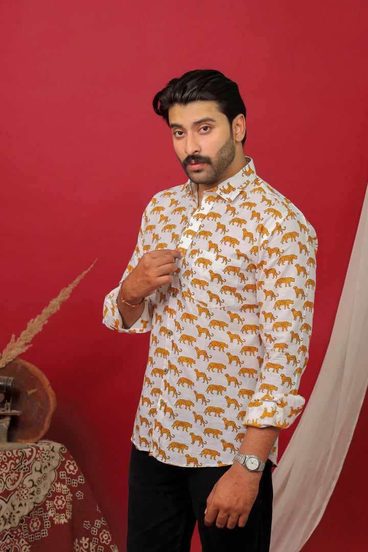 Man wearing a white tiger printed full sleeve shirt with black jeans against a red background.